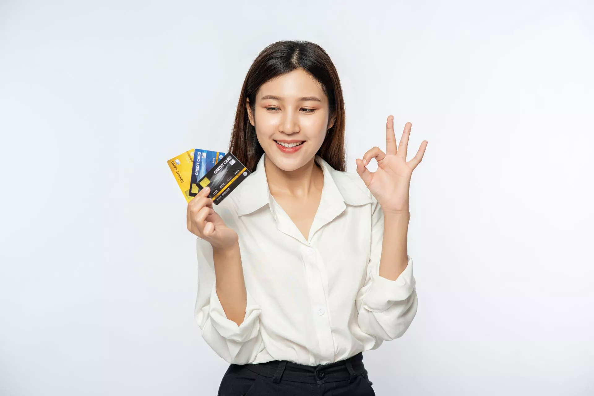 白色背景下，一名女性手持多張信用卡並比出 OK 手勢，面帶微笑，呈現對信用卡使用與消費體驗感到滿意的形象示意。