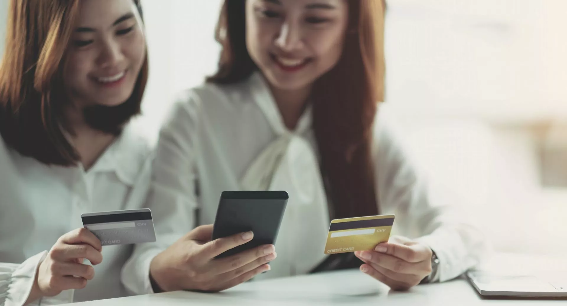 兩名女性坐在桌前使用手機與信用卡進行線上交易，畫面呈現信用卡支付與數位金融操作情境，適合用於信用卡換現金、線上刷卡與金融服務主題配圖